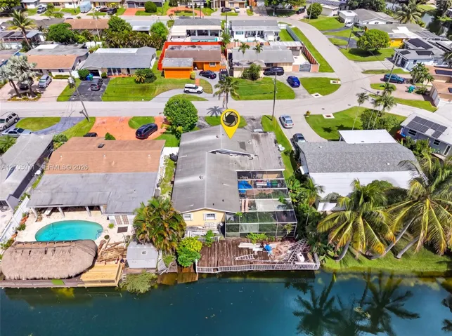 Waterfront property featuring a screened-in lanai, private dock, and established palm trees