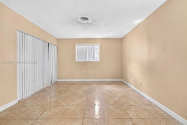 Room featuring ceramic tile flooring, vertical window blinds, and a large sliding glass door