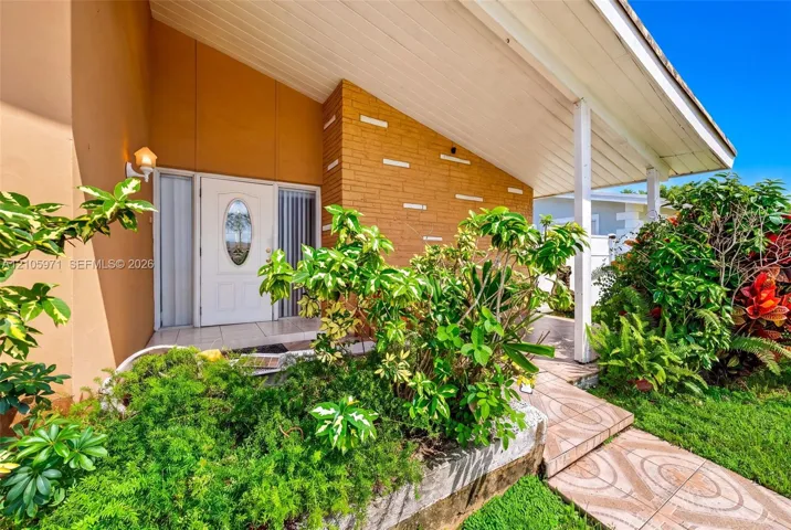 Mid-century modern facade featuring an exposed brick exterior wall, a covered entryway, a glass-panel front door with an oval window, and decorative horizontal masonry detailing