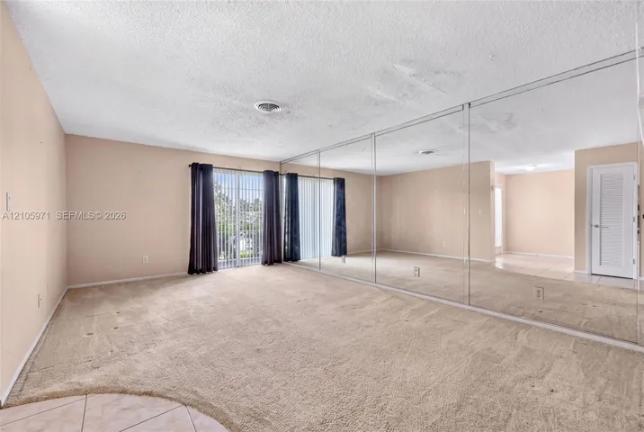 Floor-to-ceiling wall mirrors, sliding glass door, carpeted flooring, and a multi-panel interior door