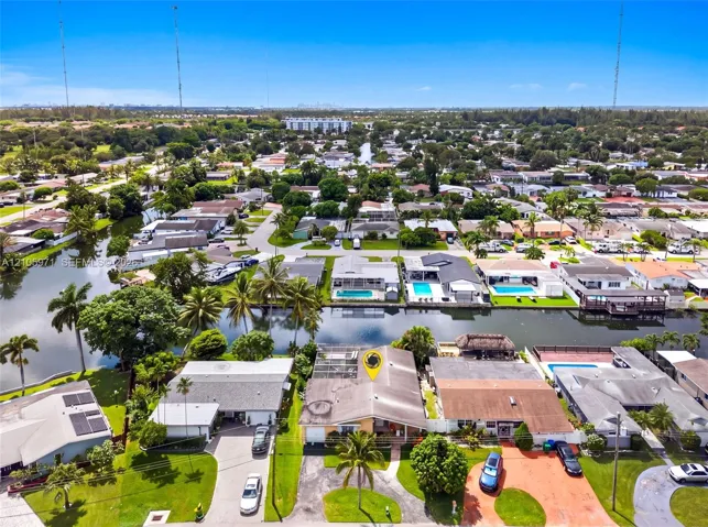 Aerial perspective featuring waterfront placement, screened rear enclosure, and mature tropical landscaping