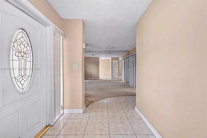 Entryway featuring a white door with an oval decorative glass insert, ceramic tile flooring, and wall-to-wall mirrored closet doors