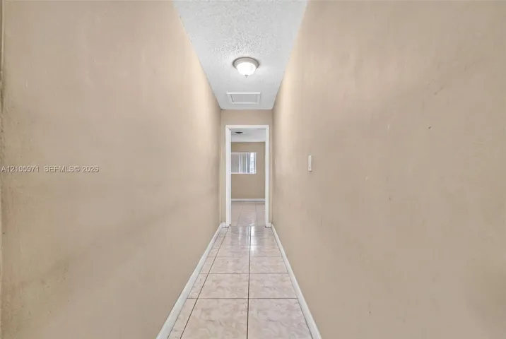Hallway featuring neutral-toned walls, tile flooring, and a ceiling-mounted light fixture