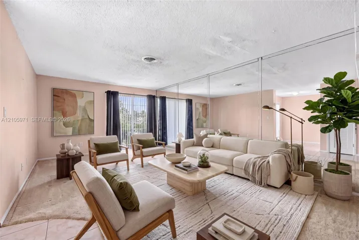 Living area featuring floor-to-ceiling wall mirror panels, sliding glass doors, and light-toned carpeting
