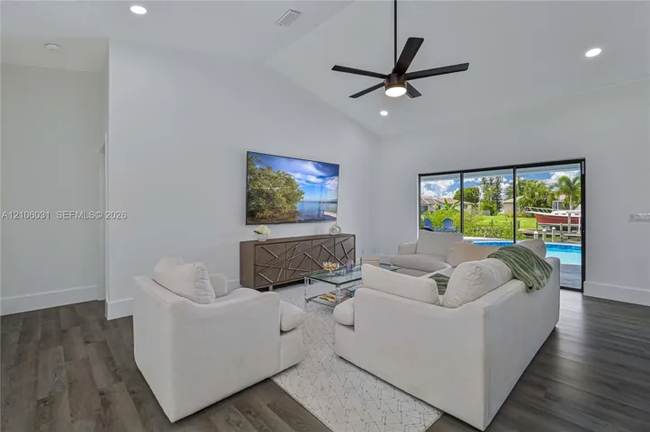 Vaulted ceilings, wood-finish flooring, recessed lighting, ceiling fan, and sliding glass doors