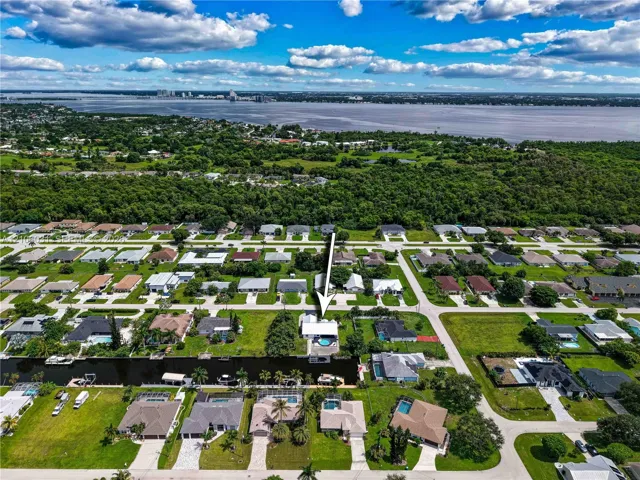 Aerial perspective of a waterfront property featuring a canal-front lot, a private swimming pool, and a bulkhead