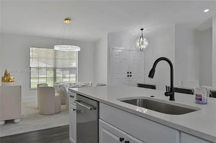 Kitchen island featuring solid surface countertops, an undermount stainless steel sink, and a matte black gooseneck faucet