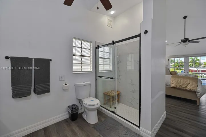 Walk-in shower featuring a frameless glass enclosure, matte black hardware, and stone-finish wall tile