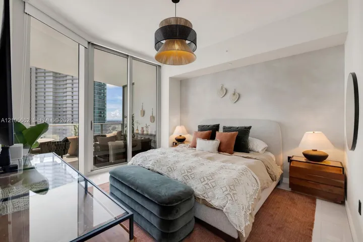 Floor-to-ceiling sliding glass doors, private balcony, contemporary multi-tiered pendant lighting, and polished tile flooring