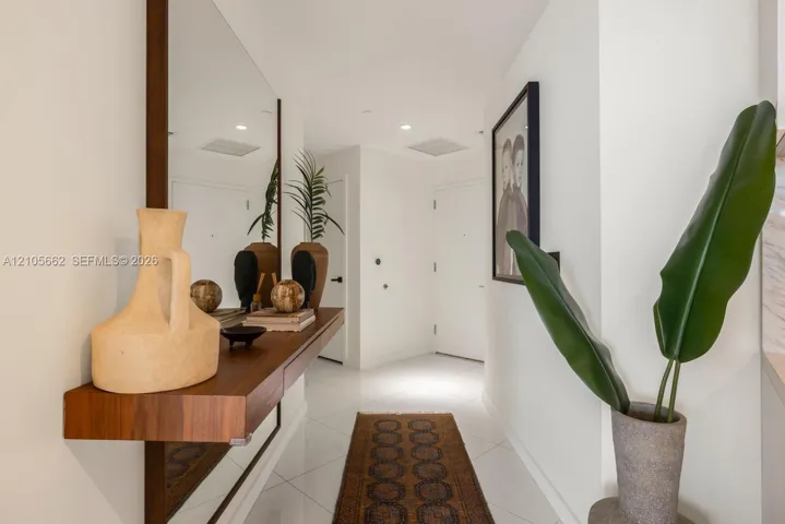 Wall-mounted wooden floating shelf, full-length mirror, recessed ceiling lighting, and polished stone-finish floor tile