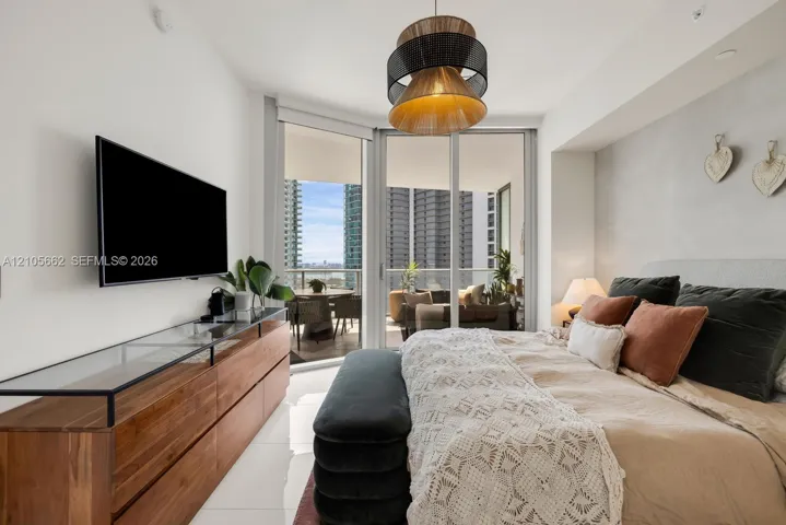 Floor-to-ceiling sliding glass doors, private balcony, polished tile flooring, and a decorative pendant light fixture