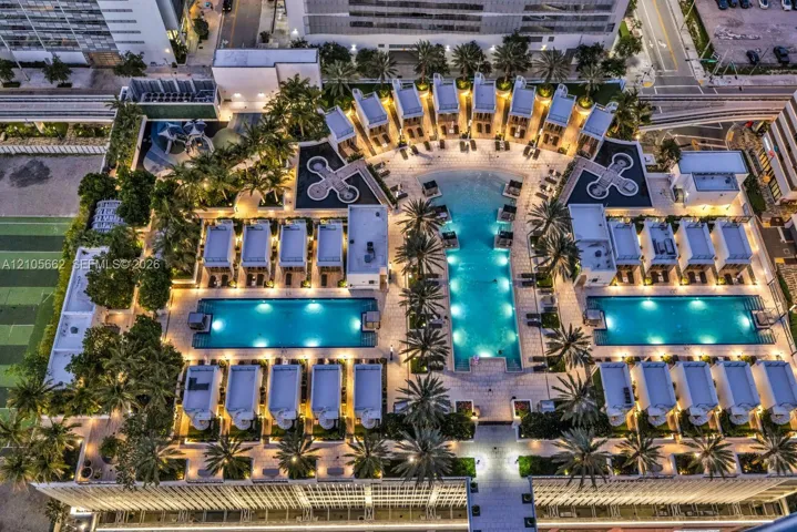 Elevated outdoor amenity deck featuring three swimming pools, landscaped terrace areas with mature palm trees, and multiple private cabana structures