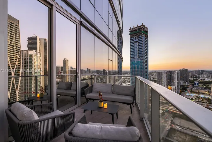 Curved balcony featuring full-height glass-paneled railings, floor-to-ceiling glass exterior wall, and wood-finish decking