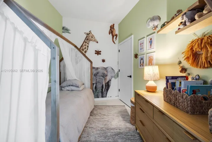 Room featuring light green painted walls, white door with matte black hardware, and wall-mounted wooden shelving