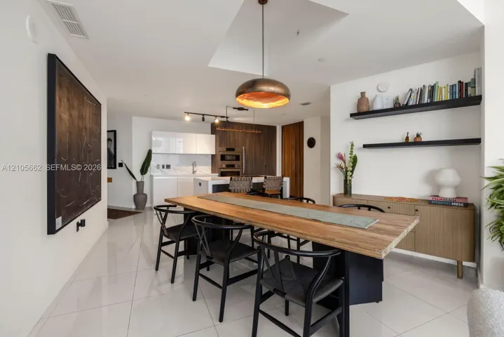 Kitchen featuring flat-panel cabinetry, built-in double ovens, stone-finish countertops, tile flooring, and metallic pendant lighting