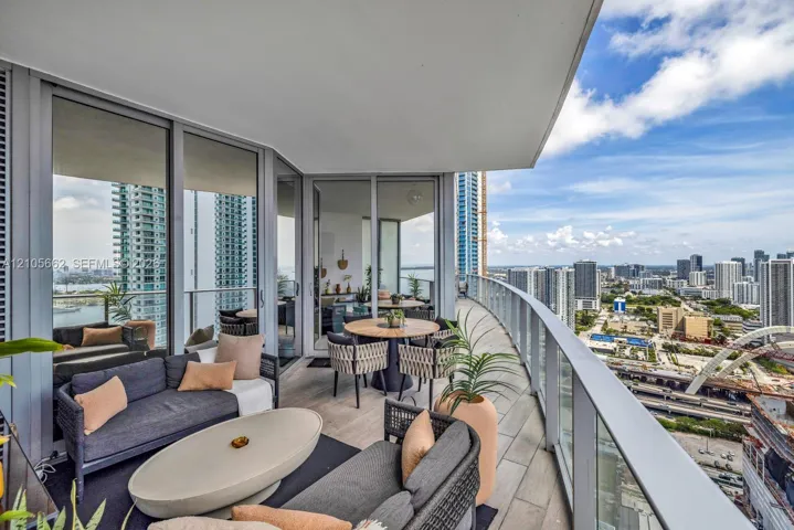 Wraparound balcony featuring large-format porcelain tile flooring, glass panel railings, and floor-to-ceiling glass sliding doors