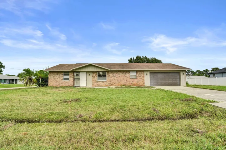 Single-story ranch exterior featuring a brick facade, shingle roof, attached two-car garage, and a concrete driveway