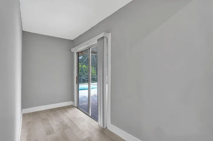 Interior space featuring wood-finish flooring, neutral wall paint, and a sliding glass door providing external access to a screened pool area