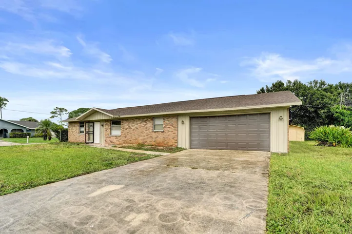 Single-story residence featuring a brick and vertical siding exterior, attached two-car garage, and concrete driveway