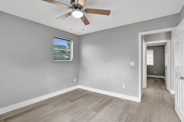 Interior space featuring light-toned wood-finish flooring, neutral wall paint, and a ceiling fan with integrated lighting