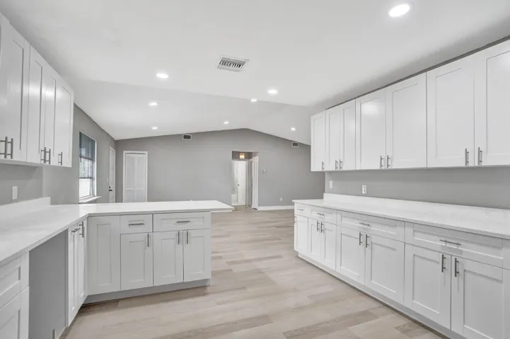 Kitchen featuring white cabinetry, light-toned countertops, wood-finish flooring, and recessed ceiling lighting