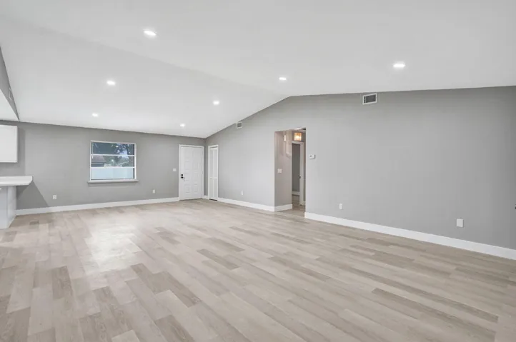 Open-concept area featuring vaulted ceilings, recessed lighting, and wood-finish flooring