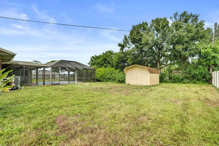 Backyard featuring a screened-in lanai, detached storage shed, and mature​​‌​​​​‌​​‌‌​‌‌​​​‌‌​‌​‌​‌​​​‌​​ trees