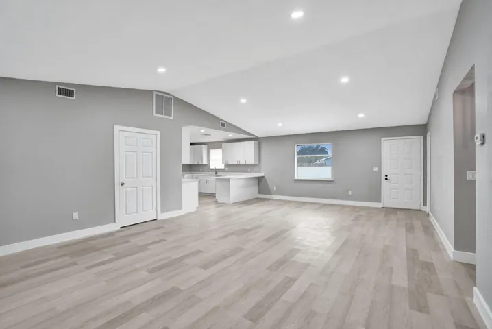 Vaulted ceiling featuring recessed lighting, wood-finish flooring, and white cabinetry