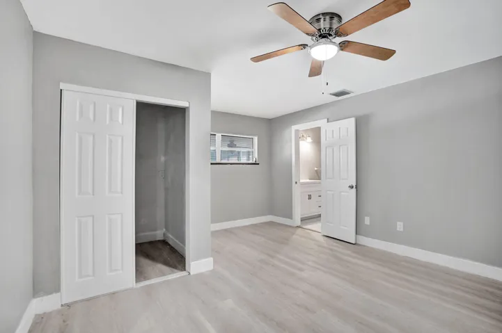 Bedroom featuring wood-finish flooring, a ceiling fan with integrated lighting, and a closet with a sliding door