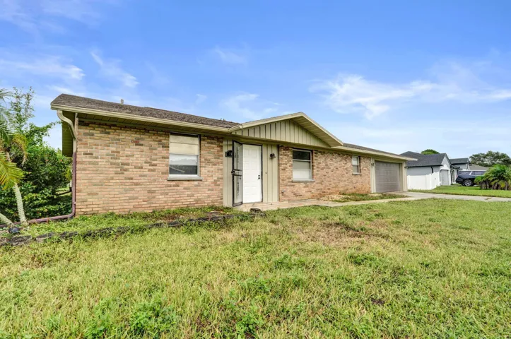 Single-story brick exterior featuring a gable roof, integrated garage, and a concrete walkway