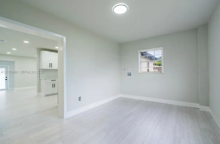 Light-toned wood-finish flooring, recessed ceiling lighting, and a single-pane window with a grid pattern