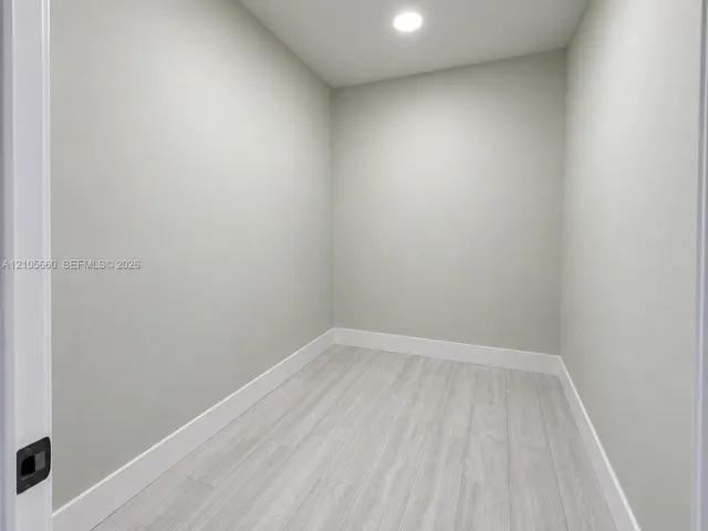 Neutral interior room featuring wood-finish flooring, light gray wall paint, and integrated recessed ceiling lighting