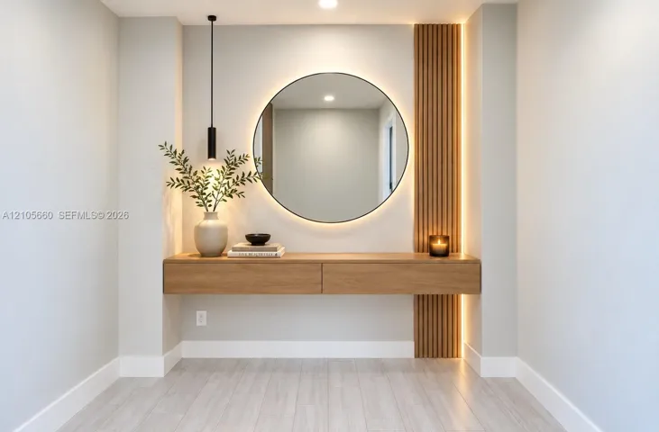 Floating wood-veneer console with dual drawers, circular backlit mirror, vertical wood-slat accent wall, and matte black pendant lighting