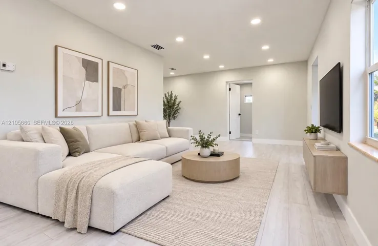Neutral-toned interior featuring wood-finish flooring, recessed lighting, and a wall-mounted floating media console