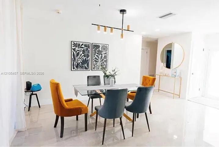Neutral-toned large-format tile flooring, contemporary matte black linear chandelier with gold accents, and recessed ceiling lighting