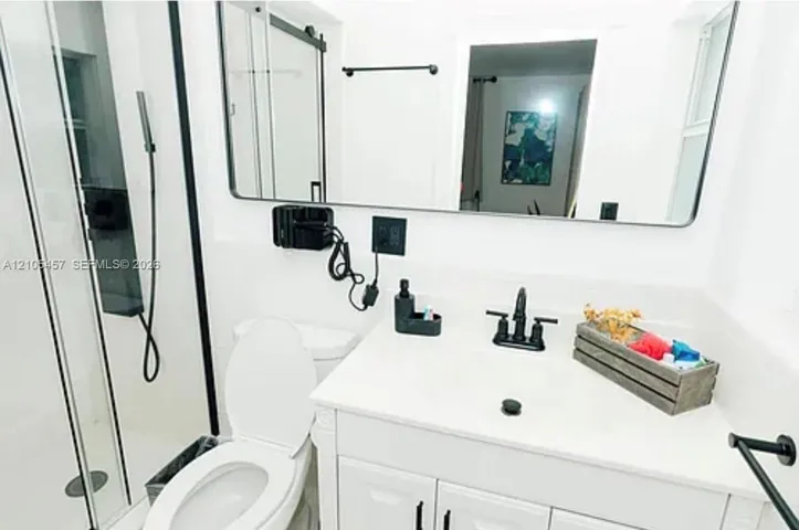 Bathroom featuring a white vanity cabinet with a solid surface countertop, matte black widespread faucet, rectangular mirror with a black frame, and a walk-in shower with a matte black trim and hardware