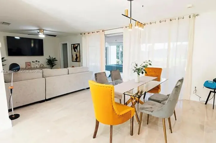 Open-concept living space featuring large-format tile flooring, a multi-light linear pendant fixture, and a ceiling fan