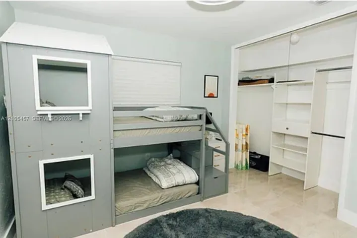 Interior room featuring light-toned tile flooring, neutral wall paint, and a sliding-door closet with built-in shelving