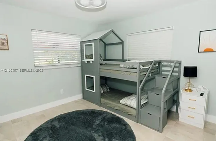 Neutral-toned tile flooring, dual windows with fitted horizontal blinds, and a central flush-mount light fixture