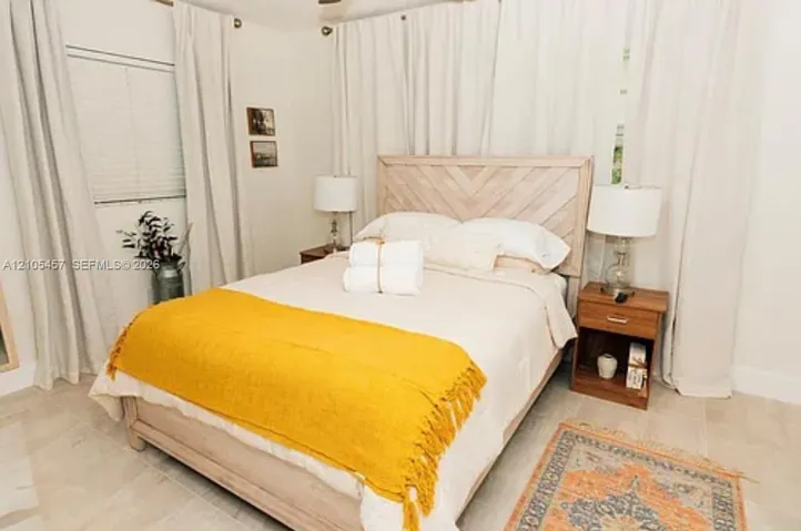Neutral-toned interior space featuring light-colored stone-finish flooring and floor-to-ceiling drapery panels