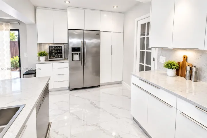 Beautifully renovated white kitchen featuring abundant cabinet space, almost all stainless steel appliances, and a wine cooler.