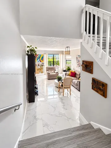Large-format tile flooring with polished finish, staircase with wood-finish treads and white balusters, metal handrail. Beautiful lake views welcome you the moment you enter the home.