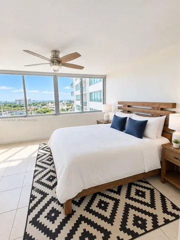 Floor-to-ceiling windows, tile flooring, and a ceiling-mounted light fixture with a fan