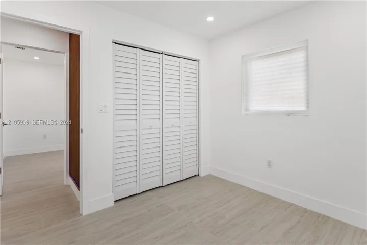 Room featuring wood-finish flooring, white walls, louvered bi-fold closet doors, and recessed lighting