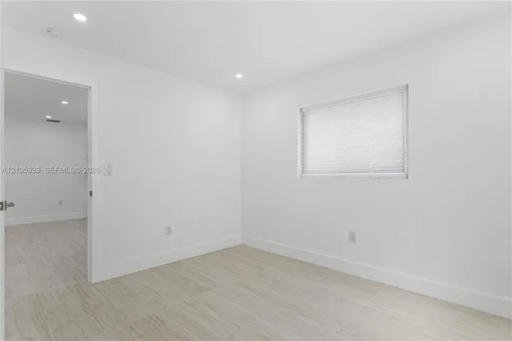 Neutral interior featuring wood-finish flooring, recessed lighting, and a window with a pleated shade
