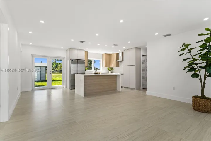 Kitchen featuring a center island, light-finish cabinetry, stainless steel refrigerator, recessed lighting, and large-format tile flooring
