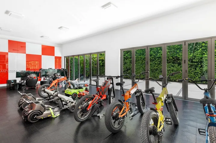 Expansive room featuring high-gloss red and white wall panels, durable rubberized diamond-plate flooring, and two sets of multi-panel aluminum-framed glass folding doors