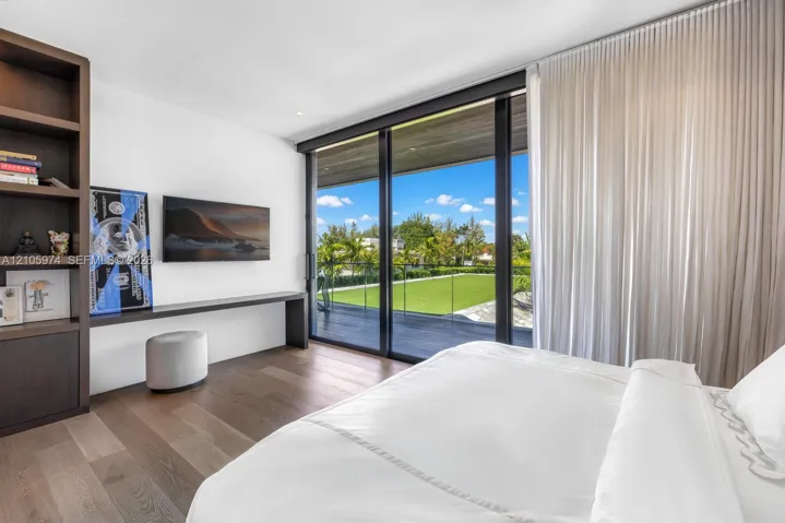 Floor-to-ceiling sliding glass doors, built-in floor-to-ceiling shelving, wood-finish flooring, and integrated wall-mounted desk