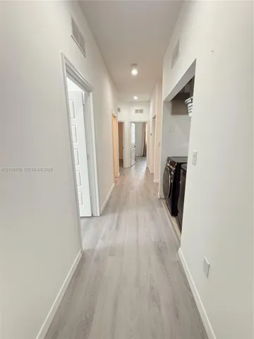 Hallway featuring wood-finish flooring, recessed ceiling lighting, and multiple panel doors