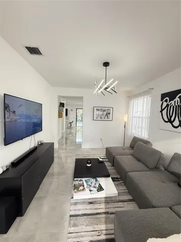 Polished tile flooring, modern multi-arm chandelier, and neutral wall finishes